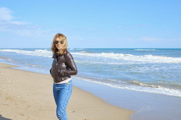 Woman standing at the beach in casual jeans and leather jacket