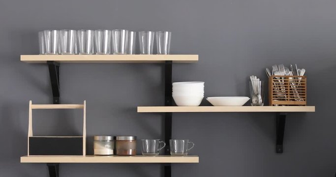 Stylish shelf with various dishware hanging on gray wall