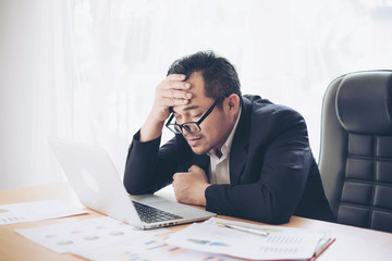 business man is stressed from work , laptop and document paperwork on office desk - business concept