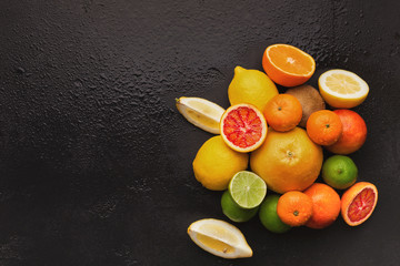 Heap of citruses on black background, top view