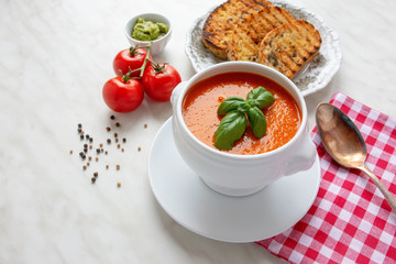 Fresh homemade tomato soup with fresh grilled Italian bread. Perfect lunch or dinner. On white table. Natural light, selective focus.