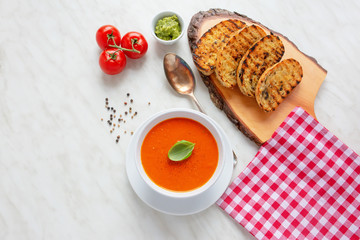 Fresh homemade tomato soup with fresh grilled Italian bread. Perfect lunch or dinner. On white table. Natural light, selective focus.