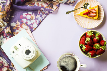 Spring breakfast with cheesecake, coffee and strawberries next to notepads and a scarf with floral print on a purple background. Copy space. Top view, flat lay