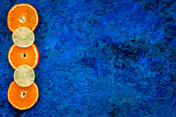 Fototapeta na wymiar Citrus frame. Oranges and lime round slices composition on blue background top view copy space