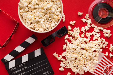 Clapperboard, 3D glasses and popcorn on red background