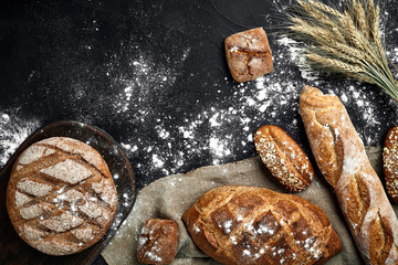 Top view of baguette, baked bread, flour and wheat spikes composition with wheat flour sprinkled...