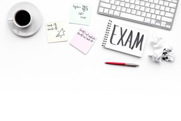 Exam concept. Lettering Exam in notebook on student's work desk on white backgrond top view copy space
