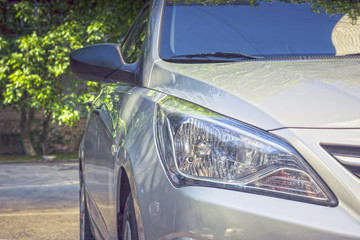 The headlight of the car in drops of morning dew on the background of trees