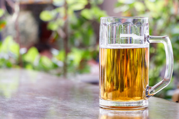 Hand holding a beer jar, outdoors.