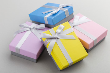 Small colorful gift boxes with ribbon bows on gray background