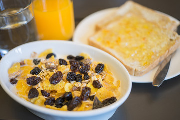 Breakfast served with water, orange juice, bread and jam, cereals milk and fruits. Balanced diet