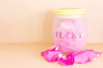 Pink rose petals in jar with message lucky