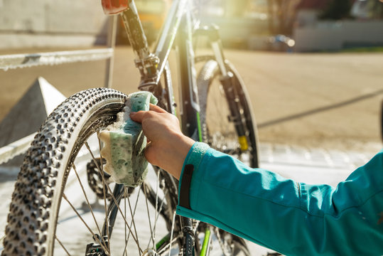 woman hand cleaning bicycle wheel with sponge.
