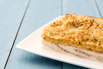 White fish casserole with cheese on blue wooden background.