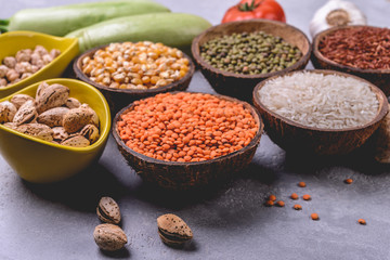 Different   grains, seeds, beans  in ceramic bowls  on grey concrete table