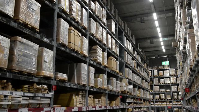 Camera moves up on shelves of cardboard boxes inside a storage warehouse