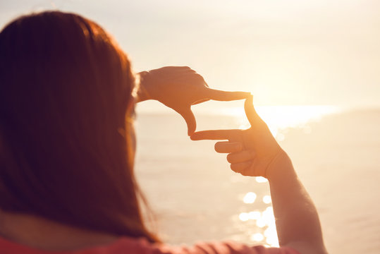 Future planning, Close up of woman hands making frame gesture with sunrise on sea summer, Female capturing the sunrise, sunlight outdoor.