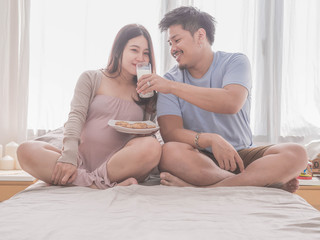 Obraz na płótnie Canvas Asian man husband take care of his pregnant wife.Beautiful pregnant woman and her handsome husband are smiling while spending time together.
