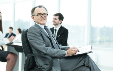 Fototapeta premium pensive mature businessman in suit with his team working behind