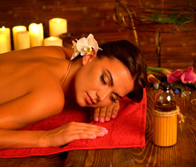 Obraz na płótnie Canvas Massage of woman in spa salon. Girl on candles background in massage spa room. Luxary interior in oriental therapy salon. Female have relax after beauty health procedure.