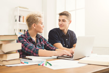 Male and female students at table full of books