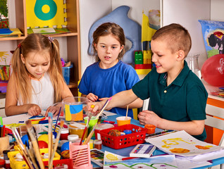 Plasticine modeling clay in children class. Teacher teaches kids together play dough and mold from plasticine in kindergarten or preschool. Competition in drawing for speed.