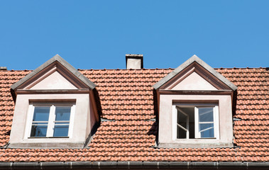 Fototapeta na wymiar tiled roof with windows against the blue sky