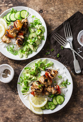 Grilled chili honey lime chicken skewers with rice and avocado salsa on wooden background, top view. Flat lay