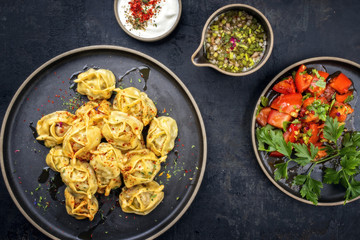 Traditionelle kasachische gedämpfte Manti mit Hackfleisch und Tomaten Salat  als Draufsicht auf einem Modern Style Teller