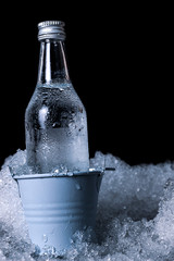 Naklejka na ściany i meble Bottle of cold vodka in bucket of ice on dark background