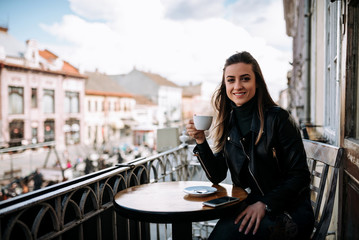 Portrait of smililng girl enjoying a cup of coffee on the balcony.