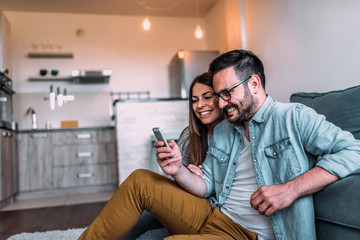 Couple looking at mobile phone at home.