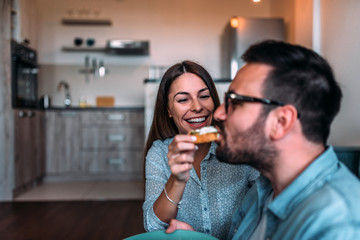 Woman feeding husband with homemade sandwich. Close-up.