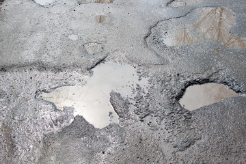 The bad asphalted road. Big pothole filled with water. Dangerous destroyed roadbed.
