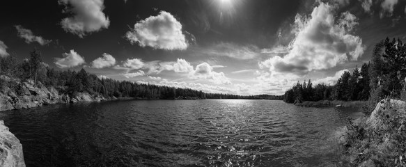 Beautiful summer quarry lake in the cliffs with cloudy sky, natural landscape background. Black and white