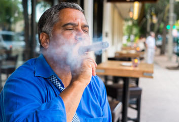 Middle age Hispanic man smoking a cigar