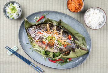 Traditioneller Thai gegrillter Tilapia Fisch mit Chili und Gemüse als Draufsicht auf einem Teller...
