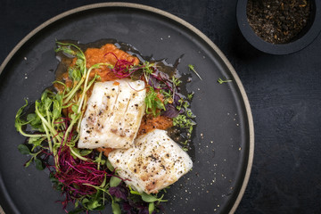 Gebratenes Kabaljau Fisch Filet mit Salat als Draufsicht  auf einem Teller mit Textfreiraum rechts