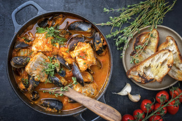 Traditionelle französisch korsische Fischsuppe mit Muscheln und Knoblauch Baguette als Draufsicht in einem Topf  - obrazy, fototapety, plakaty