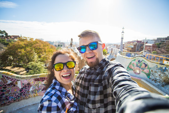Travel couple happy making selfie portrait with smartphone in Park Guell, Barcelona, Spain. Beautiful young couple looking at camera taking photo with smart phone smiling in love