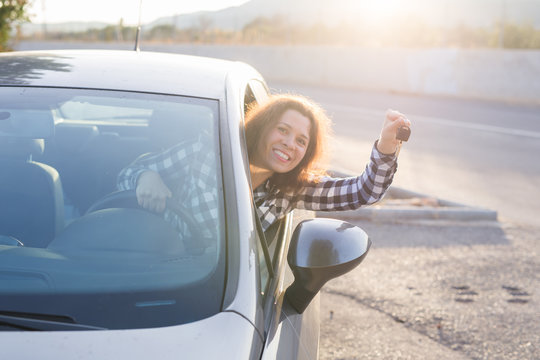 European woman behind the car wheel showing car key