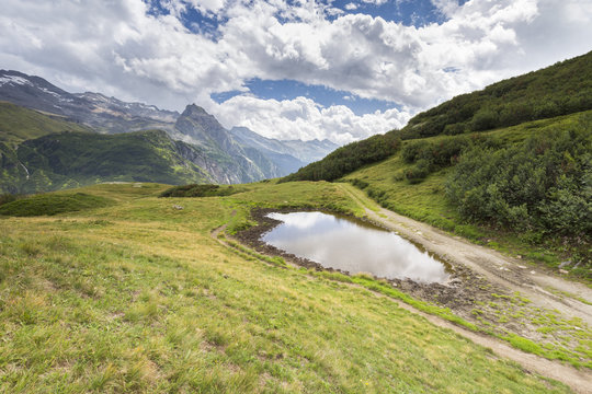 View of the Pizzo Castello, Pizzo di Cavergno, Basodino and Monte Castello reflected in a small carsic lake over Riale.  Riale hamlet, Formazza, Valle Formazza, Verbano Cusio Ossola, Piedmont, Italy.