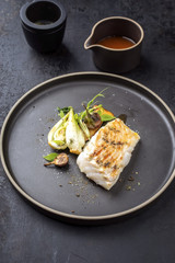 Modern Thai fried cod fish filet with bok choi and mushrooms as close up on a plate