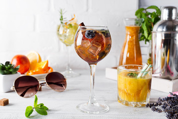 A glass of cocktail with cinnamon, berries and brown sugar and a glass with an orange cocktail or fresh and tonic