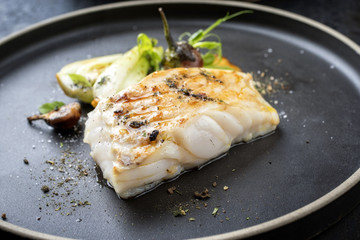 Modern Thai fried cod fish filet with bok choi and mushrooms as close up on a plate