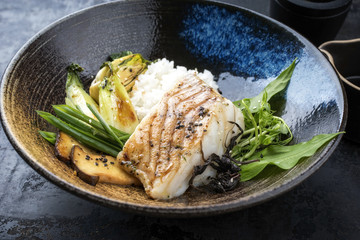 Modern Japanese fried cod fish filet with bok choi and rice as top view in a bowl