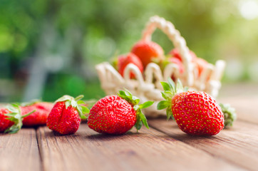 Ripe red strawberries in a basket on a wooden table
