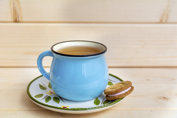 Blue Mug of Tea and Sandwich Cookies on Wooden Background