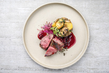 Traditional barbecue dry aged sliced venison fillet steak with potato mushroom terrine and cowberry...