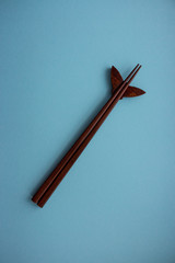 Pair of wooden chopsticks for japanese and chinese food on blue background with copy space. Travel and cuisine concept. Asia food culture concept. Sushi set of chopsticks. 